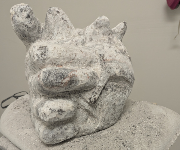 a sculpture depicting a head being held by a hand with brains oozing out of it