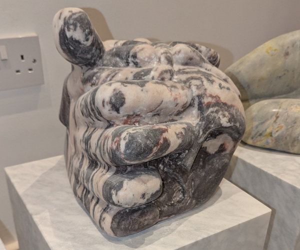 a sculpture depicting a head being held by a hand with brains oozing out of it